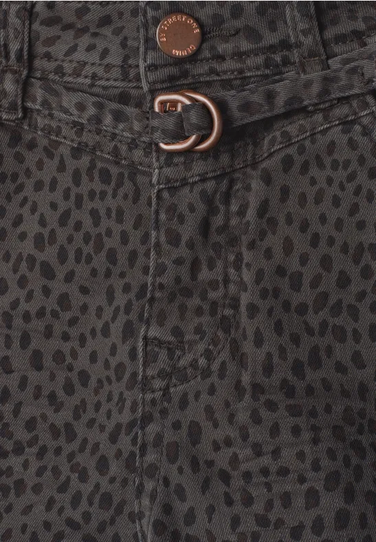 Gros plan sur un tissu foncé à pois, bouton métal et fermeture à anneau en D