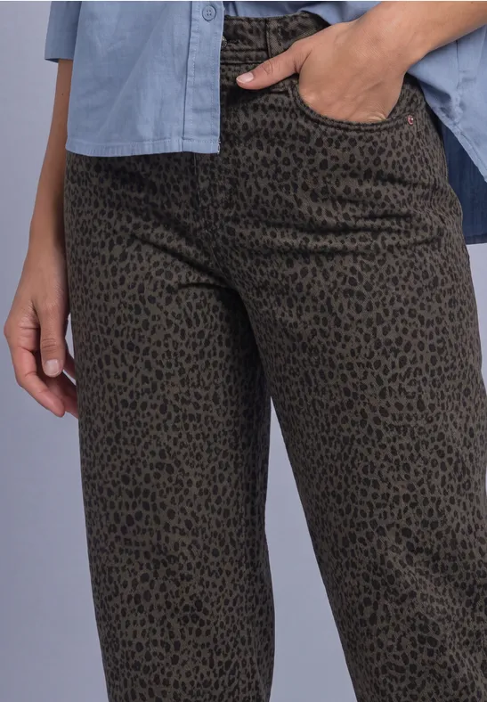 Pantalon kaki à imprimé léopard noir, main dans la poche, chemise bleu clair visible.
