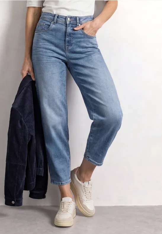 Personne porte un jean clair, baskets blanches et tient une veste sombre.