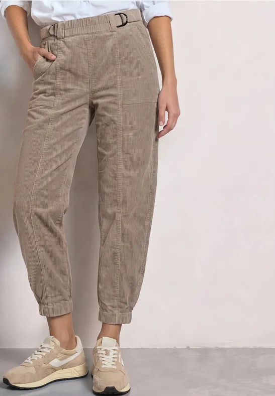 Beige Cordhosen mit elastischem Bund und Bündchen, kombiniert mit hellen Sneakern.