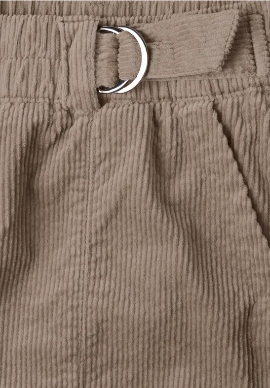 Nahaufnahme einer hellbraunen Cordhose mit elastischem Bund, Tasche und D-Ring-Gürtel.
