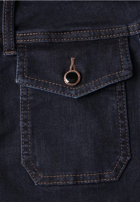 Poche de jean bleu foncé, rabat surpiqué et bouton anneau métallique en détail.