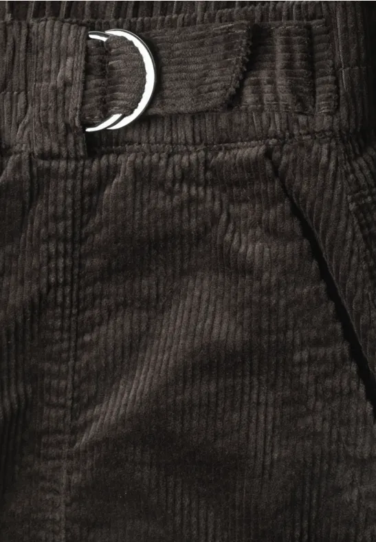 Gros plan sur un pantalon en velours côtelé marron foncé avec anneau D métallique à la taille et poche latérale.