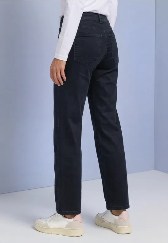 Zwarte broek met rechte pijpen, gecombineerd met witte sneakers en een loszittend shirt.