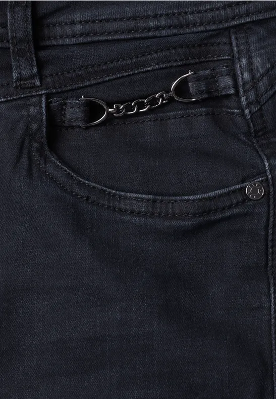 Zwarte jeans met decoratieve metalen ketting aan het kleine voorvak.