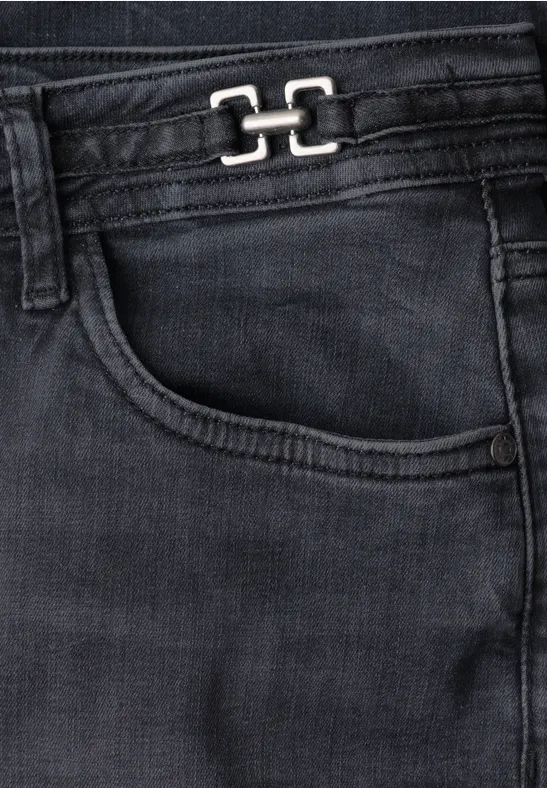 Nahaufnahme einer schwarzen Jeans mit Eingriffstasche und Metall-Logo am Bund.