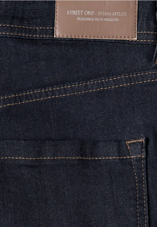 Nahaufnahme einer dunkelblauen Jeans mit kontrastfarbigen Nähten und Lederlabel.