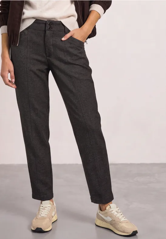 Donkergrijze, rechte broek in wolmix, gecombineerd met beige sneakers.