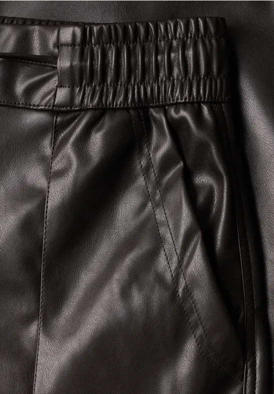 Nahaufnahme schwarzer Lederhose mit elastischem Bund und seitlicher Eingriffstasche