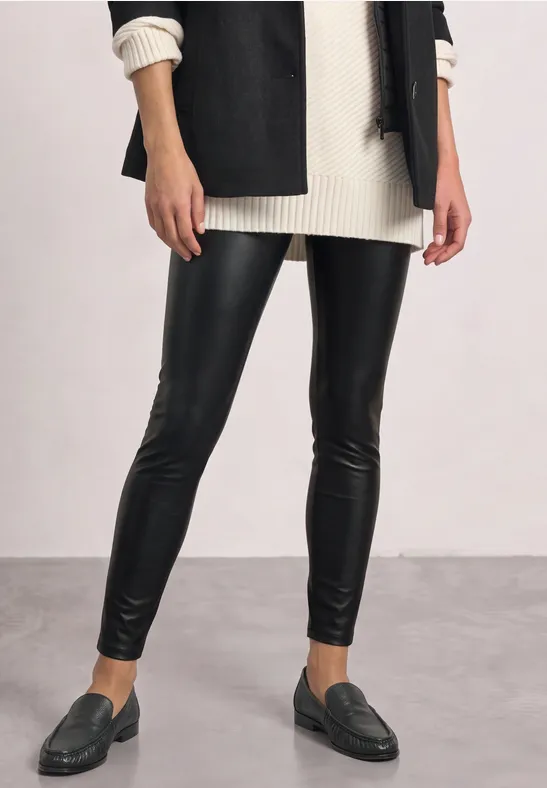 Schwarze Lederleggings mit cremefarbenem Strickpullover, schwarzem Blazer und dunklen Loafers.