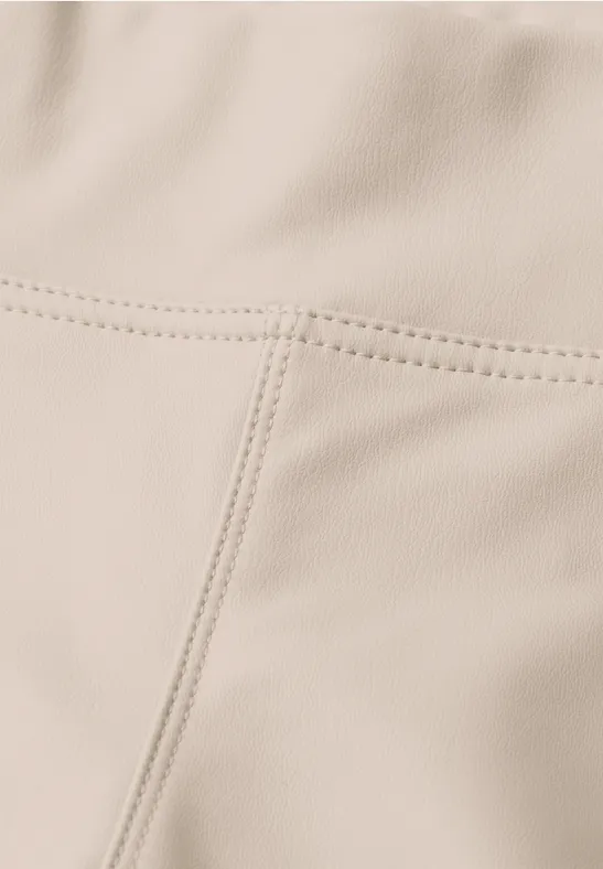 Beige Lederoberfläche mit deutlich sichtbaren Nähten in vertikaler und horizontaler Ausrichtung.