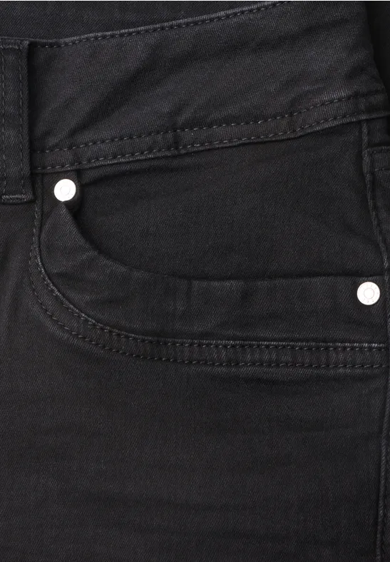 Gros plan sur poche avant de jean noir avec coutures apparentes et rivets métalliques.