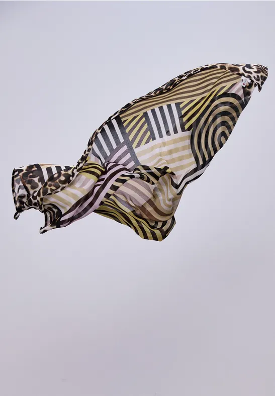 Lichte zijden sjaal met geometrisch patroon in zwart, wit, geel en pastelkleuren, zweeft elegant.