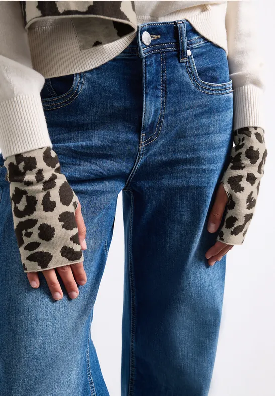 Jean taille haute bleu et mitaines beiges sans doigts à motif léopard.