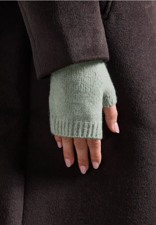 Close-up van een hand in lichtgroene vingerloze want en donkerbruine jas.