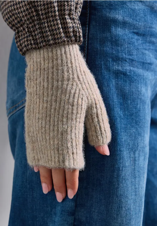 Hand met beige, gebreide vingerloze want voor een blauwe jeans