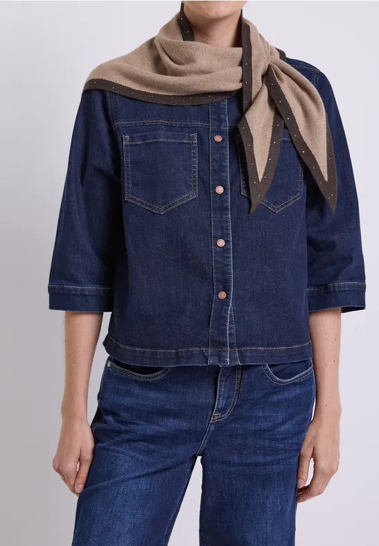 Person mit blauem Jeanshemd, Jeanshose und beigem Schal.