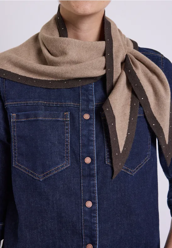 Dunkelblaue Jeansjacke und beigefarbener Schal mit Perlenakzenten, seitlich locker gebunden.