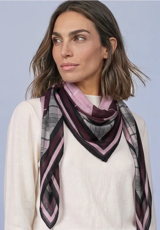 Femme aux cheveux bruns mi-longs porte un pull clair et un foulard rayé gris, noir et rose.