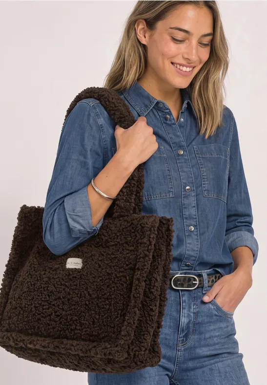Vrouw in denim met grote bruine teddy schoudertas