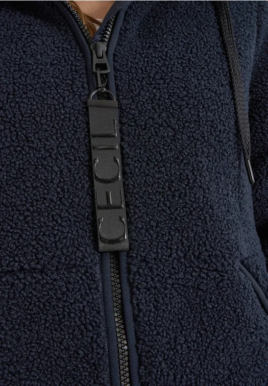 Nahaufnahme einer dunkelblauen Teddy-Fleecejacke mit Reißverschluss und Logo-Zipper-Patch.