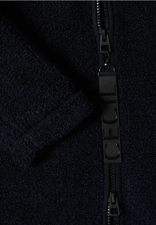 Nahaufnahme eines schwarzen Reißverschlusses an dunkelblauem Fleece-Stoff.