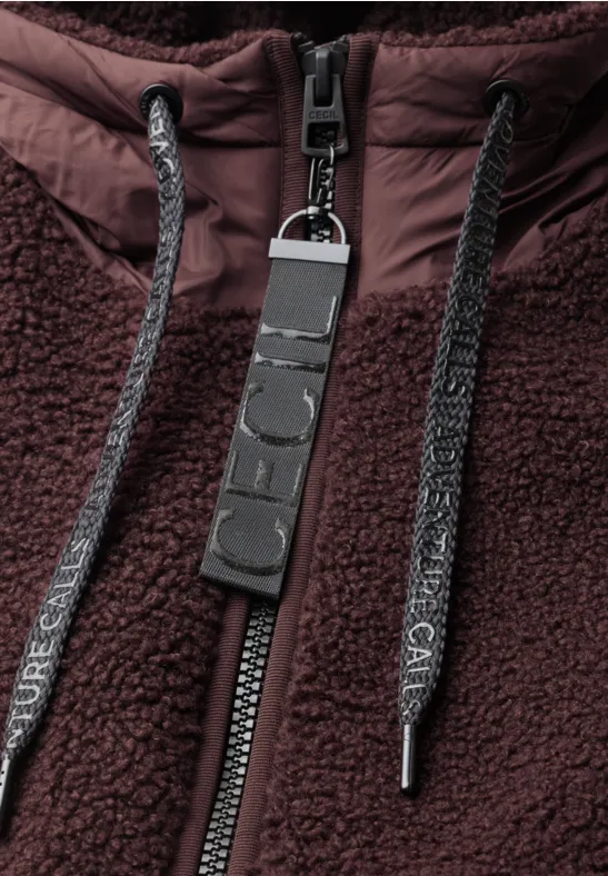Nahaufnahme einer dunkelbraunen Teddy-Fleecejacke mit Reißverschluss und Kordeln.
