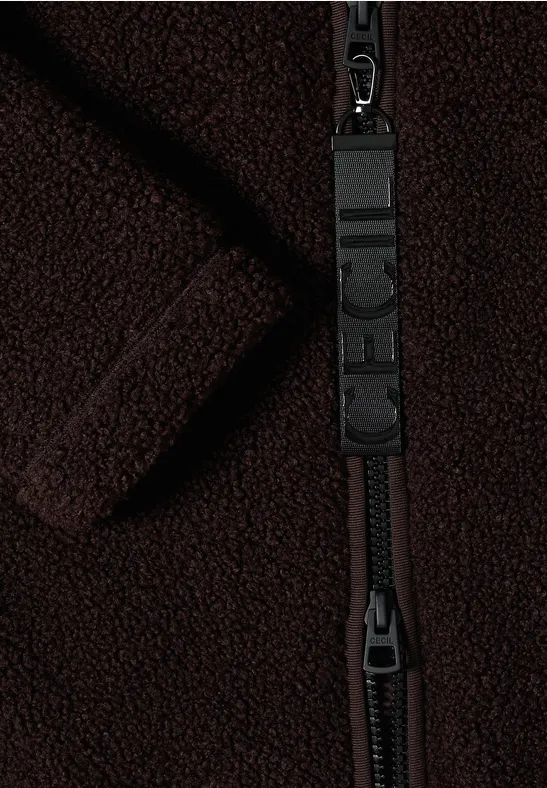 Nahaufnahme eines dunklen Fleece-Stoffes mit einem robusten Reißverschluss und Logo-Anhänger.