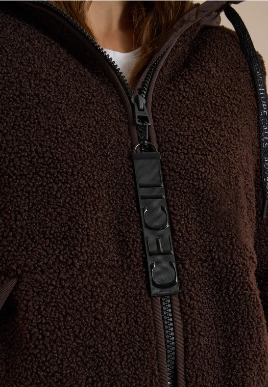 Nahaufnahme einer braunen Teddy-Fleecejacke mit auffälligem schwarzem Reissverschluss-Zipper