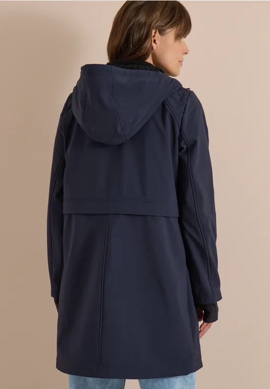Frau in marineblauer, knielanger Kapuzenjacke, von hinten fotografiert.