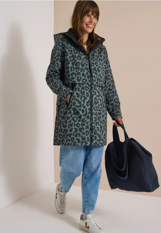 Frau in blau-grauem Leo-Mantel, Jeans und Sneakers, trägt navyblauen Shopper.