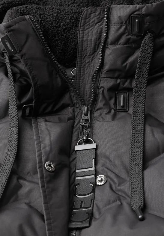 Gros plan d'une veste d'hiver noire avec fermeture éclair, boutons-pression, cordons et intérieur polaire.
