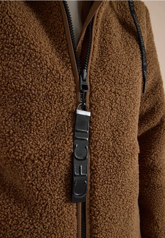 Close-up van een bruine fleecejas met rits en leren ritshanger.