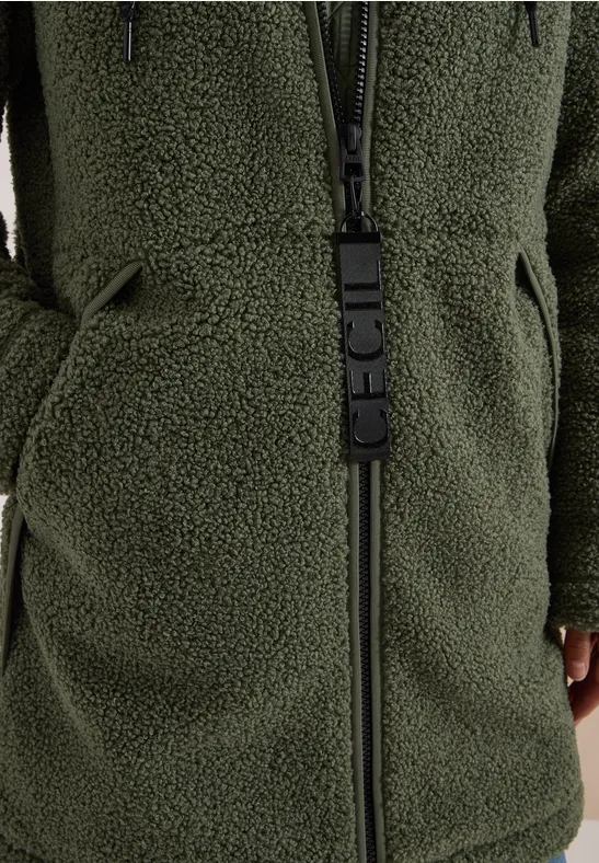Close-up van een groene teddyfleecejas met rits en zakken.