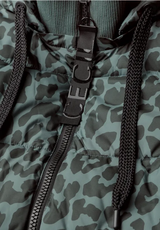 Detail van een jas met groene camouflageprint, ritssluiting, koorden en kunststofringen.