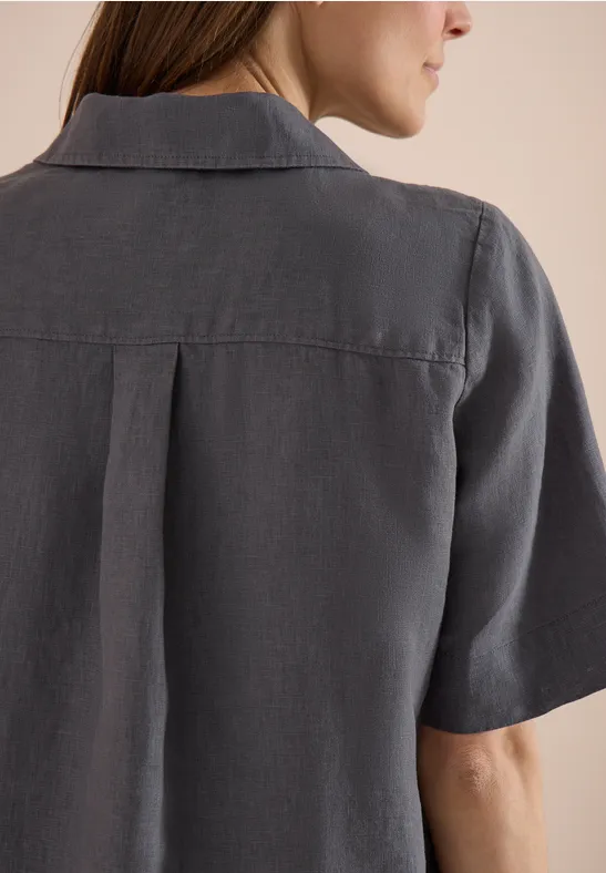 Eine Person mit grauem, kurzärmligem Hemd, Rückenansicht