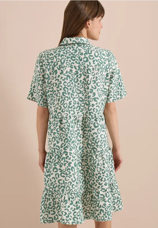 Vue de dos d’une femme portant une robe ample à manches courtes au motif léopard vert et blanc.