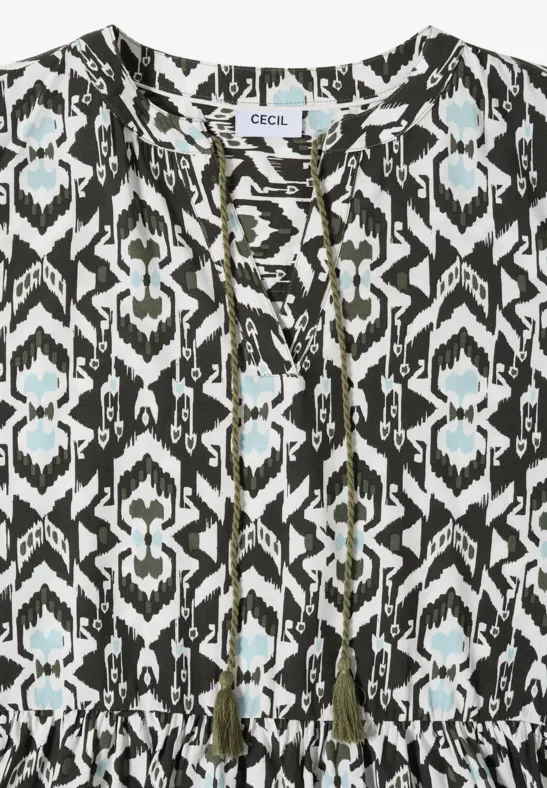 Ärmellose Bluse mit schwarz-weißem Ikat-Muster und Quasten am Ausschnitt.