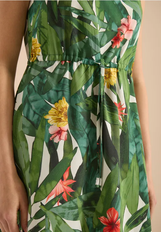 Grünes, tailliertes Kleid mit lebhaftem tropischem Blumen- und Blattmuster.