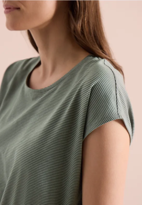 Nahaufnahme einer Frau von der Schulter bis zum Kinn in einem grünen, fein gestreiften T-Shirt.