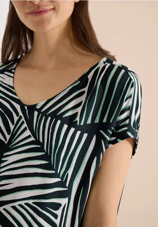 Frau in T-Shirt mit abstraktem, schwarz-weiß-grün gestreiftem Design.