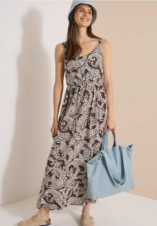 Femme en robe longue sans manches à motif cachemire marron, sac épaule bleu clair.