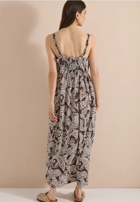 Femme vue de dos portant une robe longue à fines bretelles et motif cachemire.