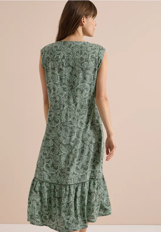 Frau von hinten in ärmellosem, grünen Kleid mit floralem Muster