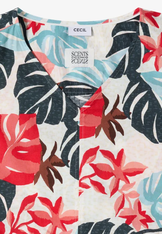 Luchtige blouse met tropisch blad- en bloemenprint in rood, blauw en turquoise op lichte achtergrond.