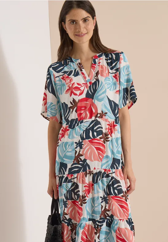 Femme en robe midi à imprimé tropical coloré.