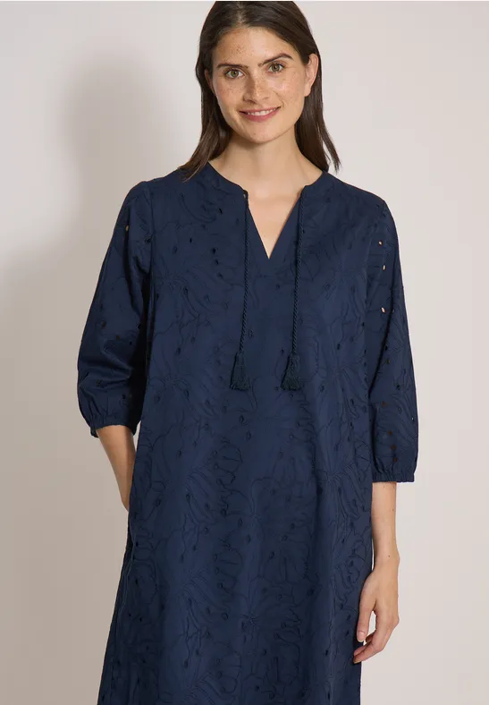 Eine Frau trägt ein marineblaues, besticktes Kleid mit V-Ausschnitt, Quasten, 3/4-Ärmeln und Taschen.