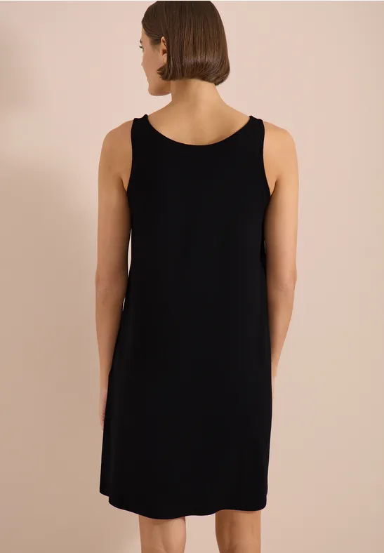 Knielanges schwarzes ärmelloses Kleid, Rückansicht vor hellem neutralem Hintergrund.