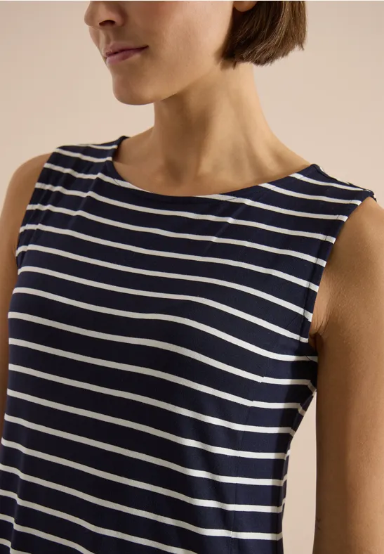 Portrait d'une femme portant un débardeur sans manches à rayures horizontales bleu marine et blanc.