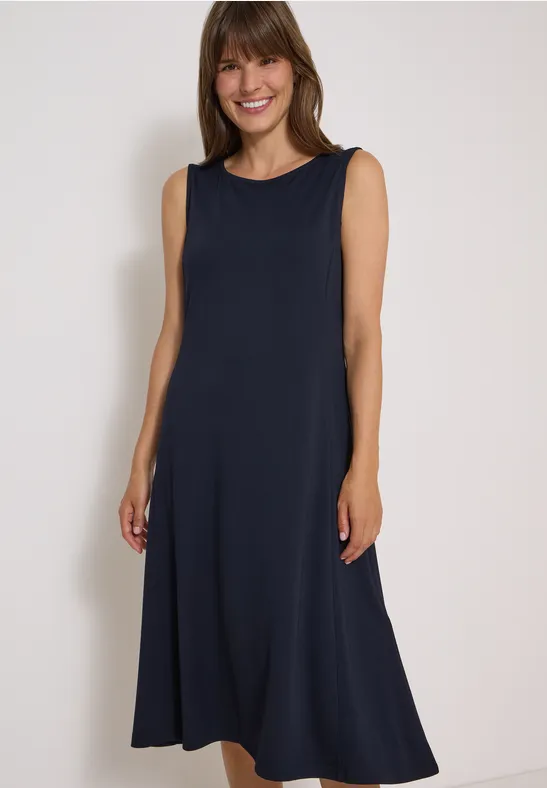 Vrolijke vrouw in een donkerblauwe, mouwloze maxi-jurk voor een lichte achtergrond.
